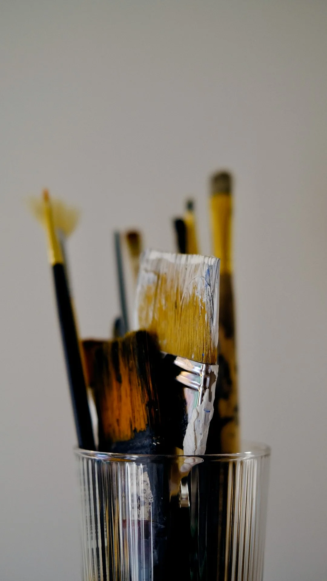 a glass filled with lots of paint brushes